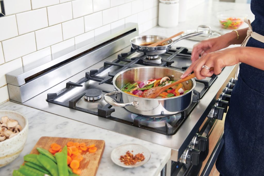Veggies stir frying on a gas stove.